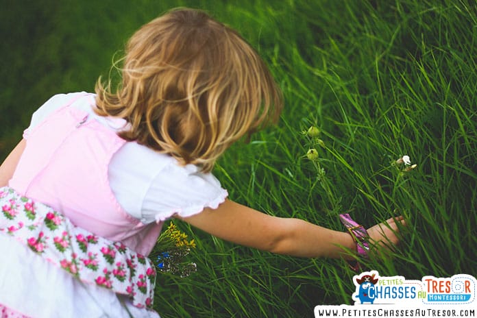 un enfants passe la main dans l'herbe verte